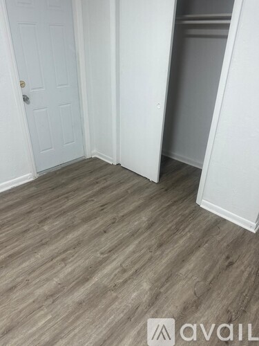 A room with a white door and a white wall with a wooden floor.
