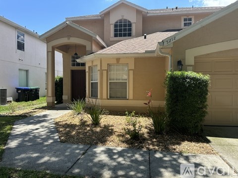A beige house with a brown roof and a brown garage door.