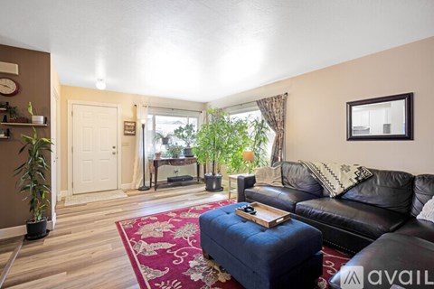 A living room with a black leather couch and a blue ottoman.