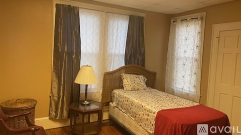 A bedroom with a bed, a table with a lamp, and a chair.