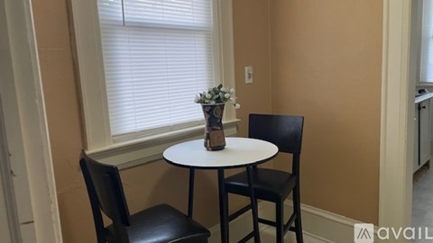 A small table with a vase of flowers on it and two chairs.