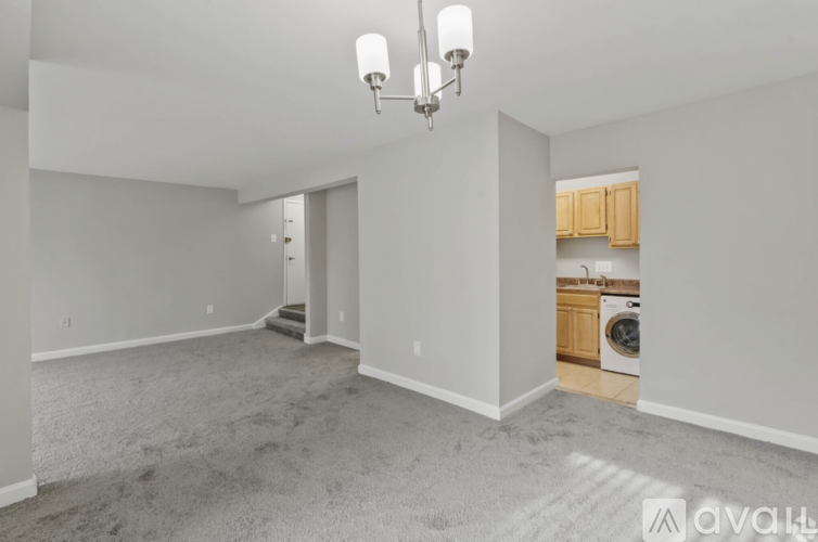 A spacious living room with a grey carpet and a chandelier.