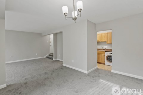 A spacious living room with a grey carpet and a chandelier.