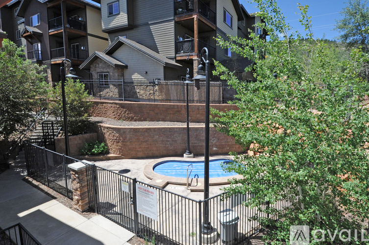 A pool surrounded by a black fence in front of a building.