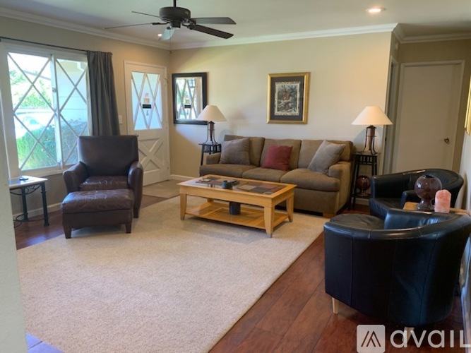 A living room with a brown leather chair, a wooden coffee table, and a beige sofa.