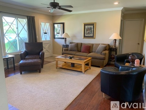 A living room with a brown leather chair, a wooden coffee table, and a beige sofa.