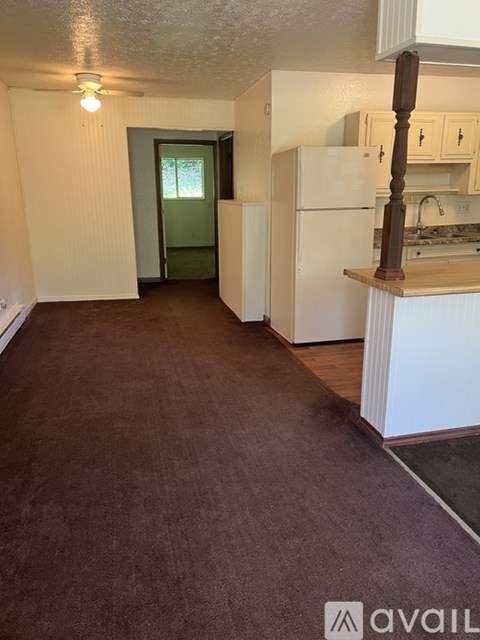 A kitchen with white appliances and a brown floor.