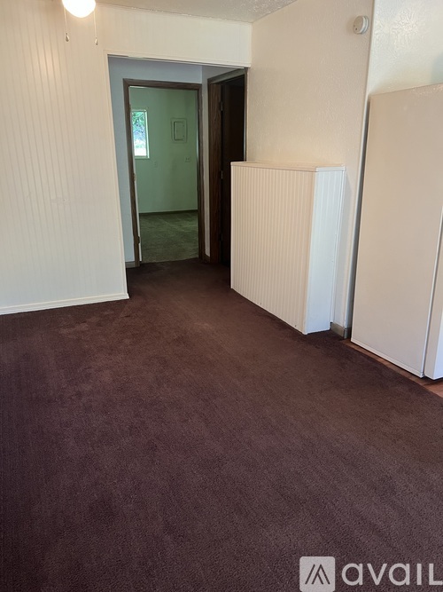 A room with a carpeted floor and a doorway leading to another room.