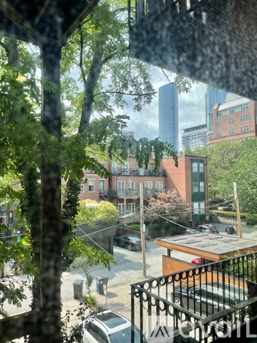 A view of a city street from a window with trees in the foreground.