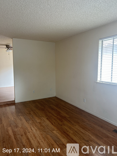 A room with wooden flooring and a window with blinds.
