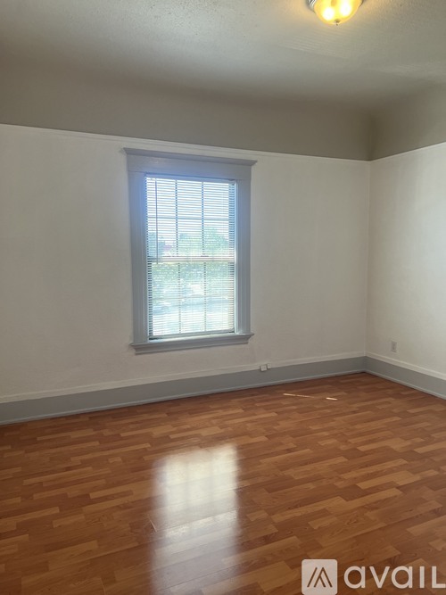 A room with a window and wooden flooring.