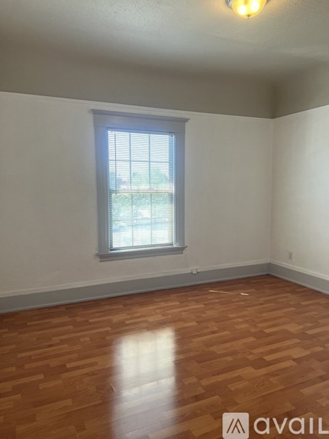 A room with a window and wooden flooring.