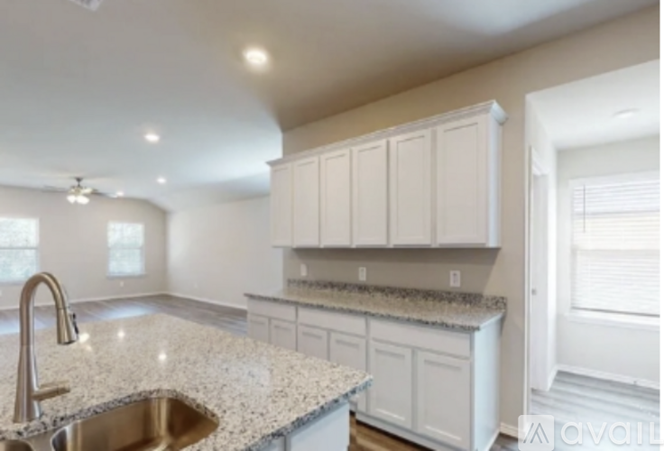 A kitchen with white cabinets and a granite countertop.