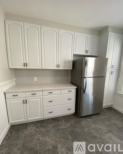 A kitchen with white cabinets and a silver refrigerator.
