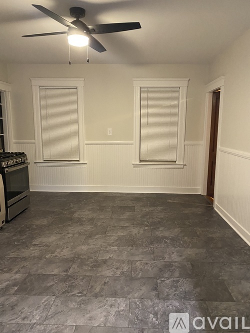 A room with a ceiling fan and grey tiled flooring.