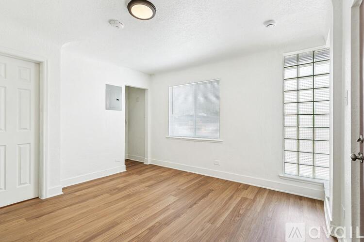 A room with wooden flooring and a window with blinds.