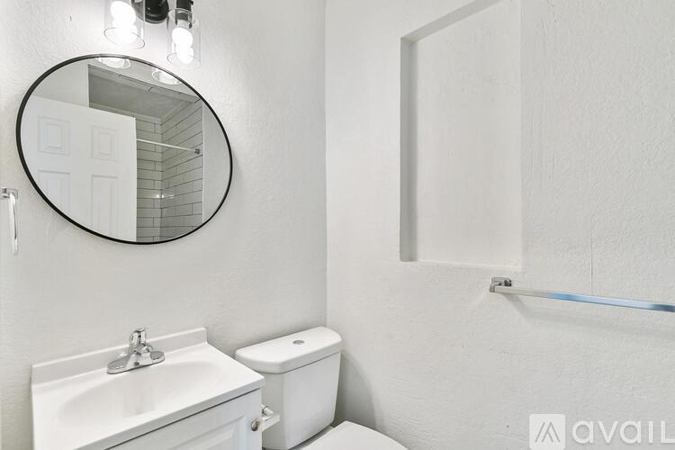 A bathroom with a toilet, sink, mirror, and a shower door.