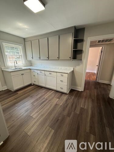 A kitchen with white cabinets and a wooden floor.