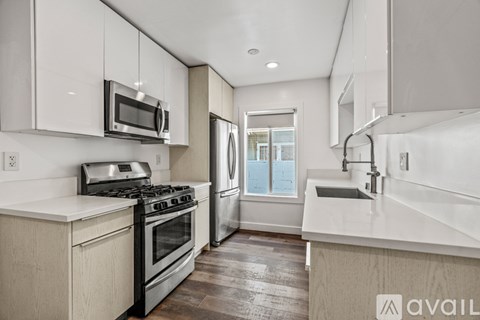 A modern kitchen with white cabinets and stainless steel appliances.