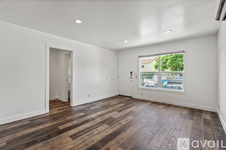 A spacious room with wooden flooring and white walls.