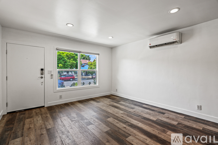 A room with a white door and a window with a view of a street and trees.