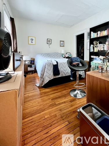 A bedroom with a bed, chair, and bookshelf.
