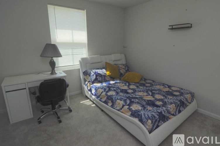 A bedroom with a bed, desk, and chair.