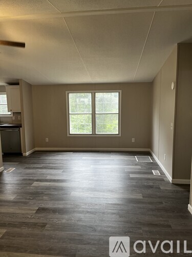 A room with a large window and wooden flooring.