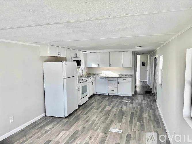 A kitchen with white appliances and cabinets in a room with wood flooring.