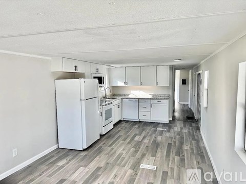 A kitchen with white appliances and cabinets in a room with wood flooring.