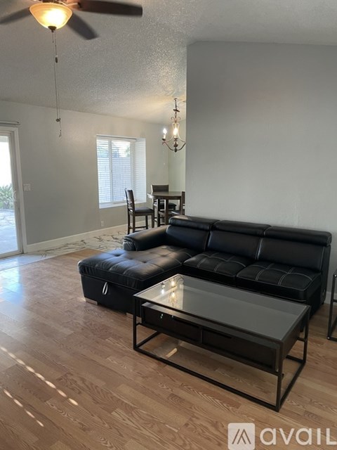 A living room with a black leather sofa and a glass coffee table.