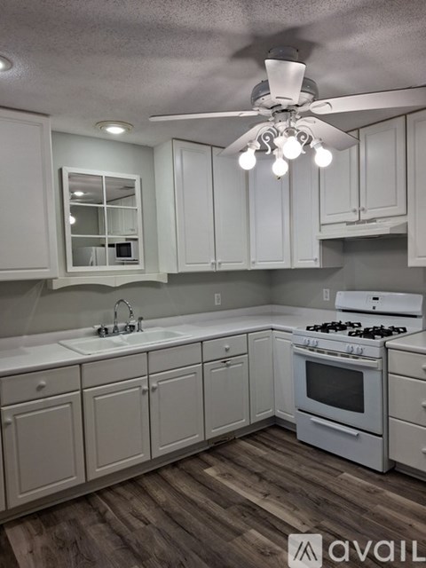 A kitchen with white cabinets and a wood floor.