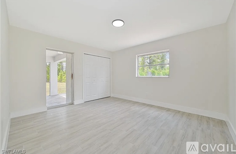 A spacious room with a sliding glass door leading to a garden.