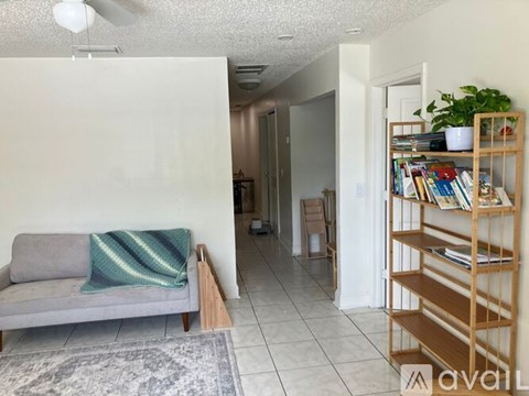 A living room with a grey couch and a wooden bookshelf.