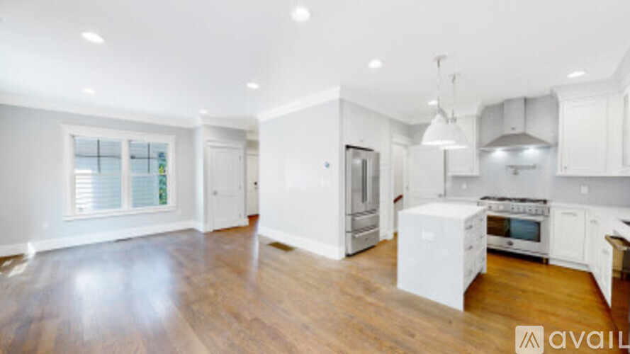 A spacious kitchen with white cabinets and a wooden floor.