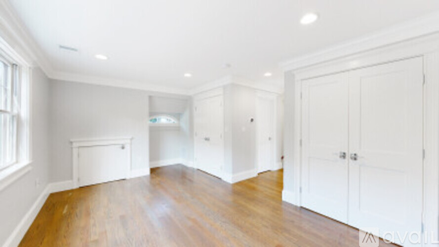 A spacious room with wooden floors and white walls.