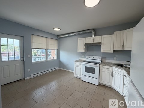 A kitchen with white appliances and cabinets is available for rent.