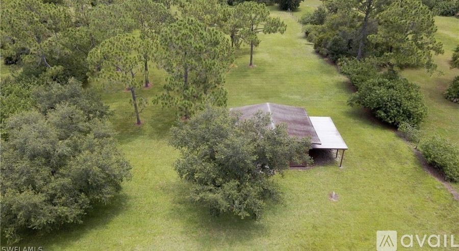 A barn sits in a field surrounded by trees.