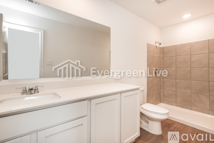 A bathroom with a white sink, toilet, and cabinets.