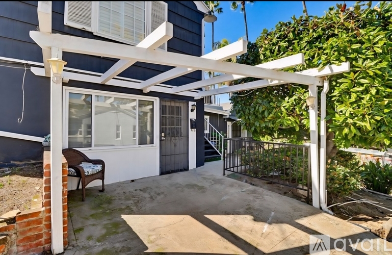 A patio with a white pergola and a brick wall.
