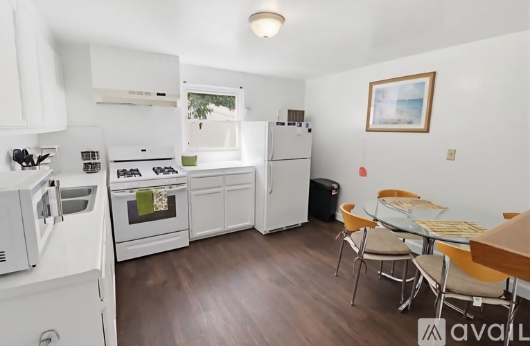 A kitchen with white appliances and a dining table with chairs.