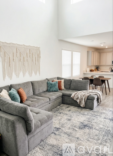 A grey sectional sofa with a grey rug in front of it.