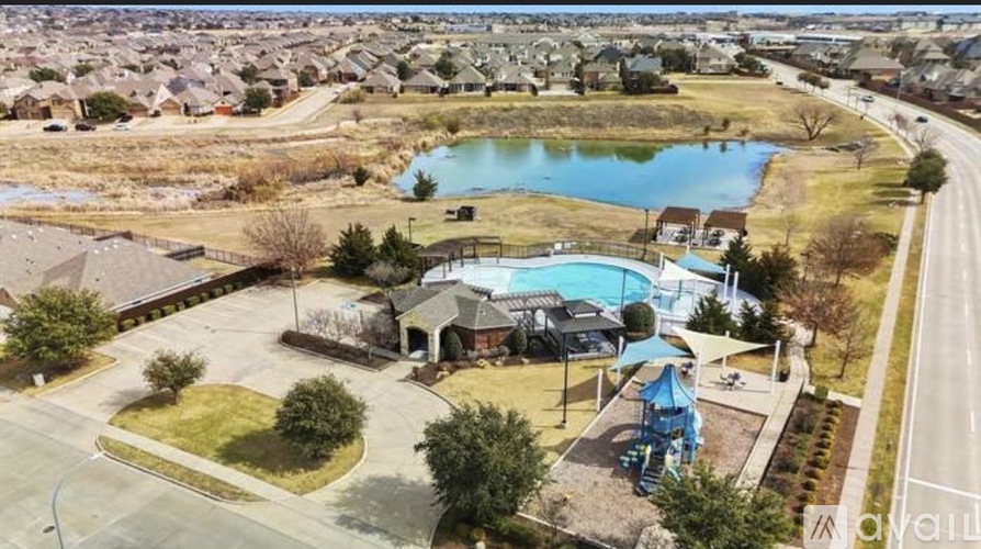 A large swimming pool surrounded by a grassy area and a playground.