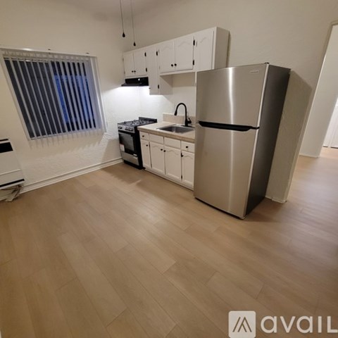 A kitchen with a refrigerator, sink, and cabinets.