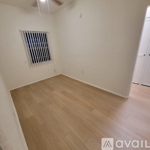 A room with wooden flooring and a window with blinds.