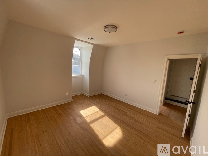 A room with wooden floors and white walls, with a door on the right side.