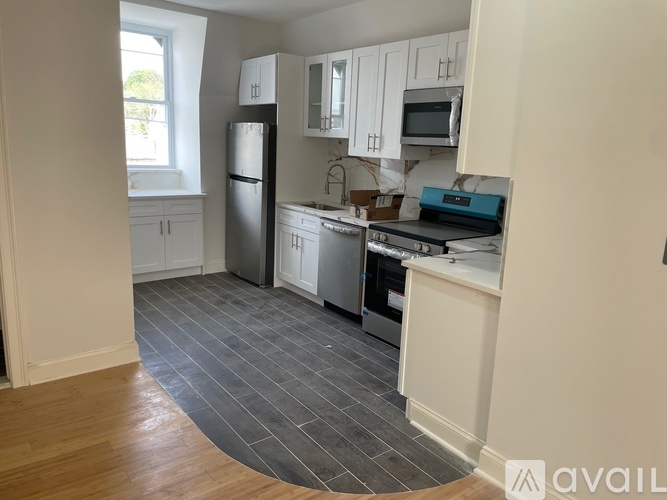 A kitchen with white cabinets and a black fridge.