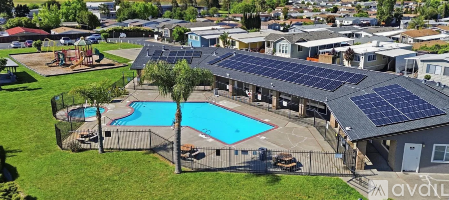 A large swimming pool surrounded by a fence and a playground.