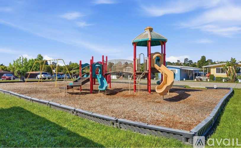 A playground with a red slide and a green and red structure.