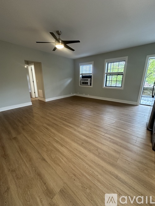 A room with a ceiling fan and wooden flooring.